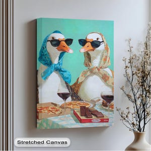 May include: Canvas art print showing two geese wearing sunglasses and headscarves, enjoying pizza and wine. The geese are depicted in a humorous, anthropomorphic style, with a light blue background. The words "Stretched Canvas" are at the bottom.