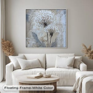 a living room with a white sofa, a coffee table, and a framed painting of a flower on the wall.