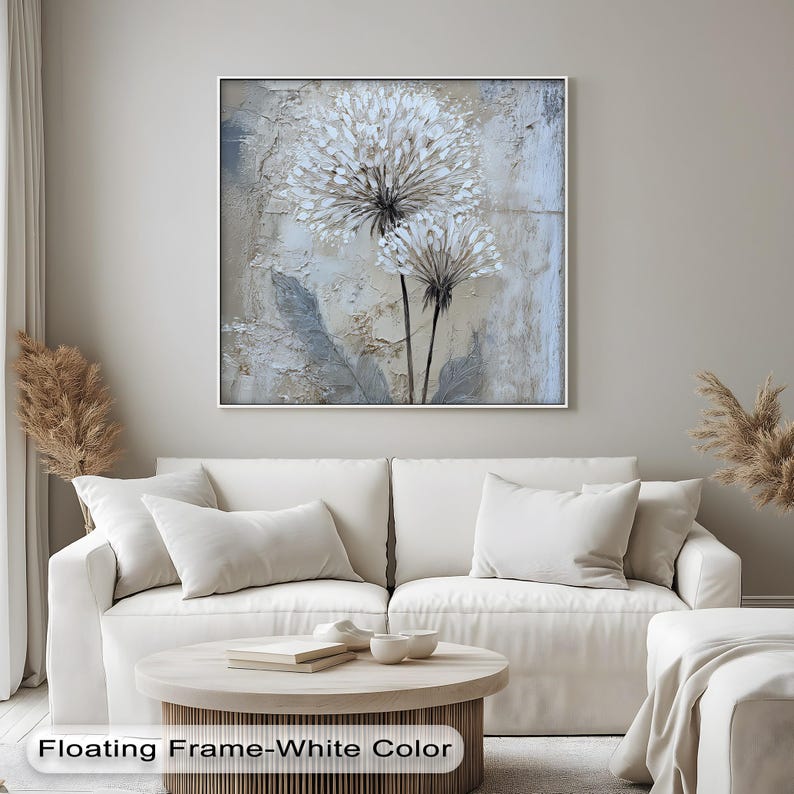 a living room with a white sofa, a coffee table, and a framed painting of a flower on the wall.