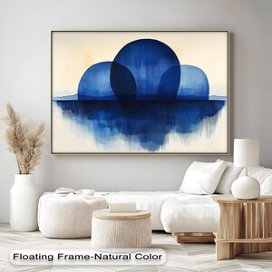 May include: Abstract wall art featuring three large blue orbs reflected in a body of water, set against a cream-colored background. The artwork is framed in a natural-toned frame and hangs above a white sofa. The text "Floating Frame-Natural Color" is at the bottom.