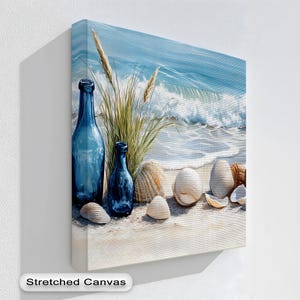 Könnte beinhalten: Ein Leinwanddruck mit einer Strandlandschaft mit blauen Glasflaschen, Muscheln und hohem Gras. Das Kunstwerk zeigt einen ruhigen Ozean mit Wellen, Sandstrand und klarem blauem Himmel. Der Text "Stretched Canvas" befindet sich unten.