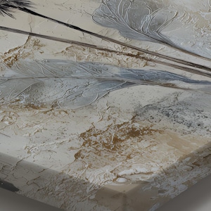 A close-up view of a stretched canvas with a textured, abstract design featuring a mix of light and dark colors, including shades of gray, brown, and beige.