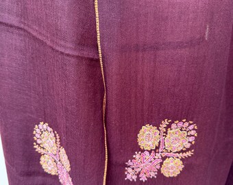 May include: A burgundy shawl with a gold border and intricate floral embroidery in shades of pink and gold.
