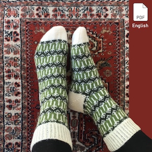 Puede incluir: Un par de calcetines de punto con un patrón geométrico verde y blanco. Los calcetines están sobre una alfombra de patrón rojo y blanco.