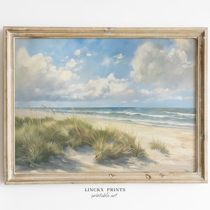 Könnte beinhalten: Ein gerahmtes Gemälde, das eine Strandszene mit blauem Himmel, weißen Wolken und grünem Gras im Vordergrund zeigt. Der Strand ist sandig und das Meer ist blau mit weißen Wellen. Der Rahmen ist aus hellem Holz.