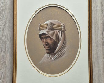 May include: Framed portrait of a person wearing traditional Middle Eastern attire. The artwork features a detailed rendering of a person with dark skin, wearing a white headdress with gold accents and a beaded necklace. The portrait is set within an oval frame.