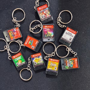 May include: Nine Nintendo Switch game cartridges attached to keychains. The games include Super Smash Bros, Zelda, Metroid, Odyssey, Pokemon, and more.