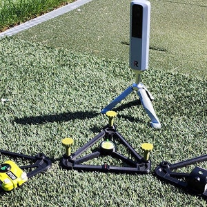 May include: Three black triangular bases with yellow knobs and a green light on each, and a silver camera on a tripod.