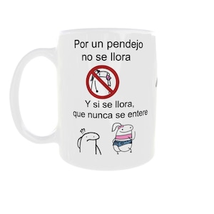 May include: White ceramic mug with a handle, featuring text and cartoon illustrations. The text reads "Por un pendejo no se llora. Y si se llora, que nunca se entere." The mug has a humorous theme.