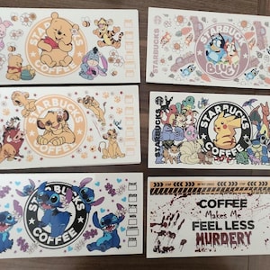 May include: A collection of Starbucks coffee cup sleeves featuring various cartoon characters, including Winnie the Pooh, Simba, Stitch, and Pokemon. The sleeves are white with colorful illustrations and the Starbucks logo.