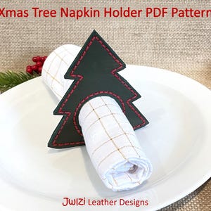Puede incluir: Un servilletero en forma de árbol de Navidad verde oscuro con costuras rojas, que sostiene una servilleta a cuadros blanca y dorada enrollada sobre un plato blanco. El texto "Xmas Tree Napkin Holder PDF Pattern" está en la parte superior.
