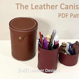 May include: Two leather canisters, one brown and one burgundy, with a white stitching detail. The burgundy canister is filled with pens, pencils, and other office supplies. The text "The Leather Canister PDF Pattern" is at the top of the image.