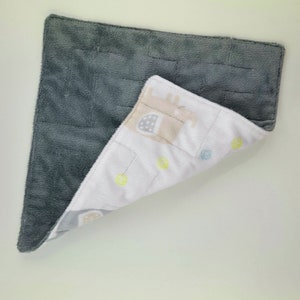 May include: A soft, grey and white baby blanket with a pattern of elephants and colourful dots. One side of the blanket is grey and the other side is white.