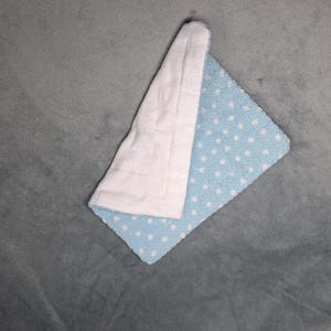 Könnte beinhalten: Eine hellblaue Babydecke mit weißen Punkten. Eine Seite der Decke ist weiß und die andere Seite ist blau mit weißen Punkten.