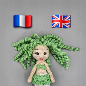 May include: A handmade crochet mermaid doll with green curly hair, a green top and skirt, and a white tail with green accents. The doll has a neutral skin tone and is set against a gray background. The text "LaCollectionPerrine" is visible.