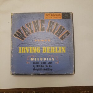 Könnte beinhalten: Ein blaues und oranges Schallplattenalbumcover mit dem Text "RCA Victor Musical Smart Set" und "Wayne King Plays Irving Berlin Melodies". Das Albumcover zeigt eine Liste von Songs, darunter "Remember", "All Alone", "Always", "Say It With Music", "Blue Skies" und "A Pretty Girl Is Like A Melody".