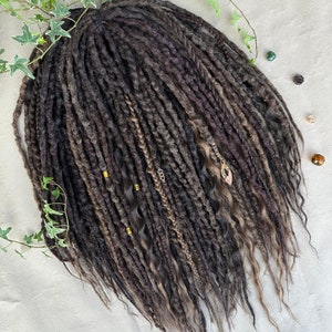 May include: A long, thick, dark brown and grey synthetic dreadlock hair extension with gold beads.