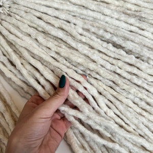 Peut inclure: Un paquet de longues dreadlocks synthétiques blanches. Les dreadlocks sont douces et moelleuses, et elles sont disposées en un tas soigné.