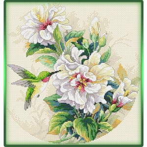 May include: A cross-stitch pattern featuring a vibrant green hummingbird hovering near large, white, ruffled flowers with pink centers and green leaves. The design is set against a cream-colored fabric background with a thin green border frame.