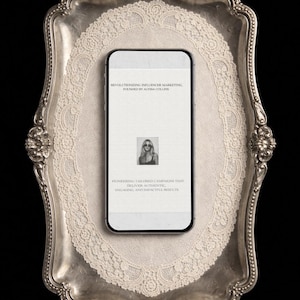 Może przedstawiać: Smartfon wyświetlający tekst o marketingu influencerów, w tym "Revolutionizing Influencer Marketing, Founded by Alyssa Collins". Telefon spoczywa na srebrnej tacy z koronkową serwetą, na czarnym tle.