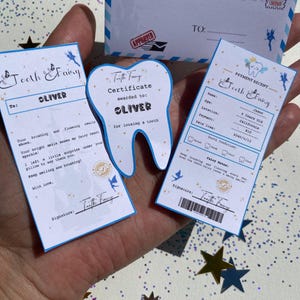 May include: A Tooth Fairy set includes a letter, certificate, and payment receipt. The envelope is blue and white with a stamp and the text "From: Tooth Fairy." The certificate is tooth-shaped and says "OLIVER." The receipt is for a lost tooth.