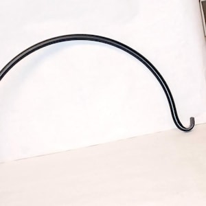 May include: Black metal hook with a curved shape and a hook at the end. The hook is designed to hang items from a wall or ceiling.