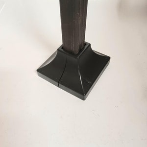 May include: Black metal post with a square base. The base is made of two separate pieces that fit together.
