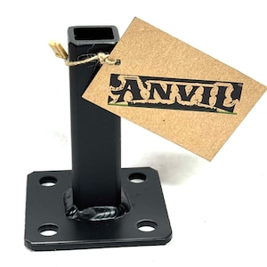 May include: Black metal post with a square top and a base with four holes. A brown tag with the word "ANVIL" is attached with twine. The post is likely for construction or support.