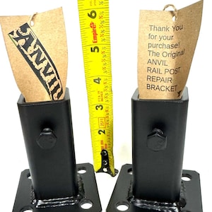 May include: Two black metal rail post repair brackets with four mounting holes on each square base. The brackets are 6 inches tall. A yellow measuring tape is visible in the background.