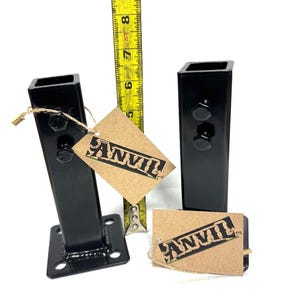 May include: Two black metal brackets with square bases and a square top. The brackets are about 6 inches tall and have two bolts on the top. The brackets are labeled "ANVIL".