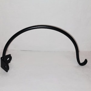May include: Black metal hook with a curved design. The hook is attached to a square base with a hole in the center.