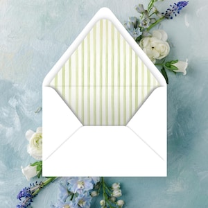 May include: A white envelope with a light green and white striped interior. The envelope is open, revealing the patterned lining. White and blue flowers are arranged around the envelope against a light blue background.