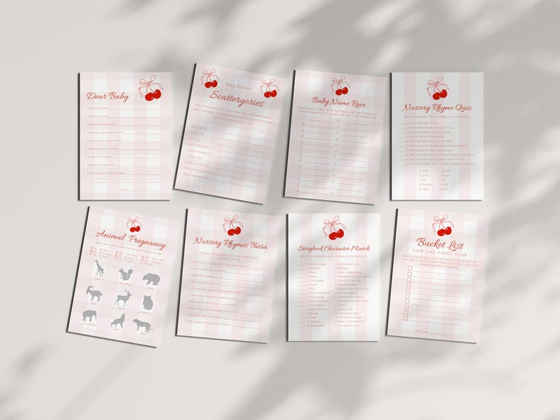 May include: A collection of eight baby shower game sheets. Each sheet features a pink and white gingham or striped pattern with red cherry illustrations. Games include "Dear Baby," "Scattergories," and "Baby Name Race."