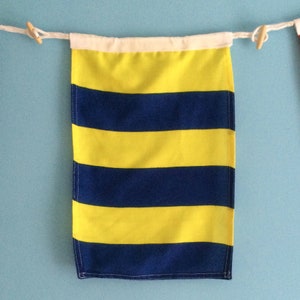May include: A yellow and blue striped nautical signal flag. The flag is made of fabric and has a white header.