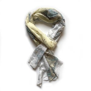 May include: A white and yellow scarf with a nautical map print. The scarf is folded and tied in a knot.