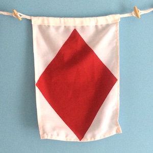 May include: A white nautical signal flag with a large red diamond in the center.