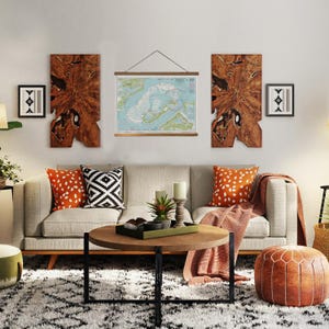 May include: A living room scene featuring a light gray sofa with orange and black patterned pillows. A round wooden coffee table sits in front of the sofa, with a map hanging above it. Decorative wooden wall art and a patterned rug complete the space.