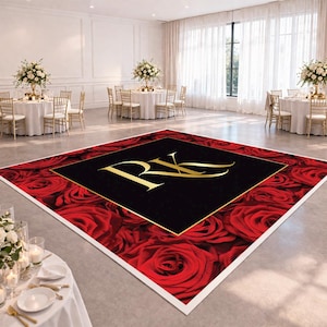 May include: A square dance floor wrap featuring a pattern of deep red roses surrounding a central black square with a gold border. The letters RK are printed in large gold serif font in the center of the black square, set in a bright event hall.