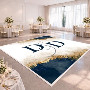 May include: A rectangular dance floor featuring a white base, navy blue and gold watercolour design, and the navy blue letters "D&D". The floor is in a large room with round tables, chairs, and floral centrepieces.