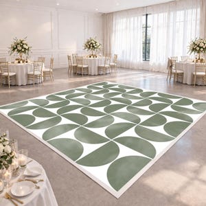 May include: A large, rectangular dance floor with a repeating pattern of sage green semi-circles on a white background. The dance floor is set up in a large, well-lit event space with round tables and floral centerpieces.