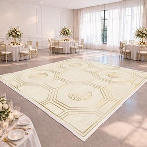 May include: A large, rectangular dance floor with a cream-colored background and a geometric pattern in gold. The design includes octagons and seashell motifs. The floor is set up in a large, well-lit event space with round tables and floral centerpieces.