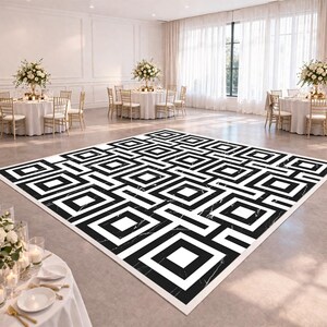 May include: A black and white geometric patterned dance floor in a large event space. The floor features a repeating square and rectangular design. The room has round tables with white tablecloths and floral centerpieces. The space is well-lit with natural light.