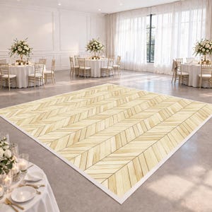 May include: A light-colored wooden dance floor with a herringbone pattern is the focal point of a large, well-lit event space. Round tables with white tablecloths and floral centerpieces are set up for guests. The room has large windows and white walls.
