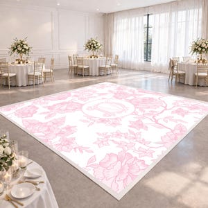 May include: A large, rectangular dance floor with a white background and a pink floral pattern. The design includes large peony-like flowers and a central circular emblem. The dance floor is set in a spacious event hall with round tables and floral centerpieces.