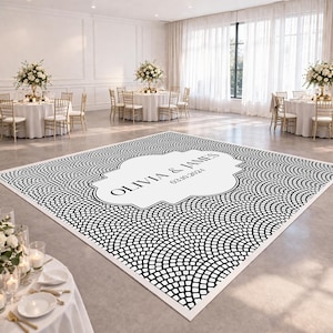 May include: A black and white patterned dance floor with the names "OLIVIA & JAMES" and the date "03.10.2021" in a white decorative frame. The dance floor is in a large room with round tables, chairs, and floral centerpieces.