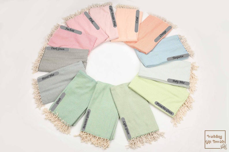 May include: A variety of striped Turkish towels in different colors, including pink, light green, turquoise, and baby blue. The towels are arranged in a circle with the color names written on each towel.