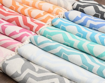 Pode incluir: Uma pilha de toalhas coloridas com um padrão de chevron. As toalhas estão dobradas e dispostas em um arco-íris de cores, incluindo rosa, laranja, azul e verde.