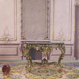 May include: An ornate console table with a black marble top, painted in gold. The table features a carved, rococo design and stands on four legs.