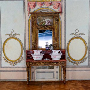 May include: A miniature dollhouse bathroom with a white and gold patterned wallpaper, a wooden vanity with two porcelain pitchers and basins, and a framed mirror with a painted scene above it.