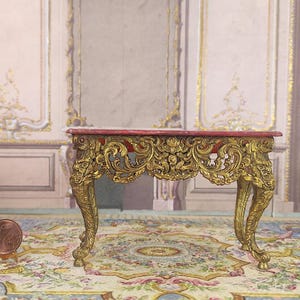 May include: A miniature ornate gold and red table with intricate carvings and scrolled legs. The table is on a patterned rug.